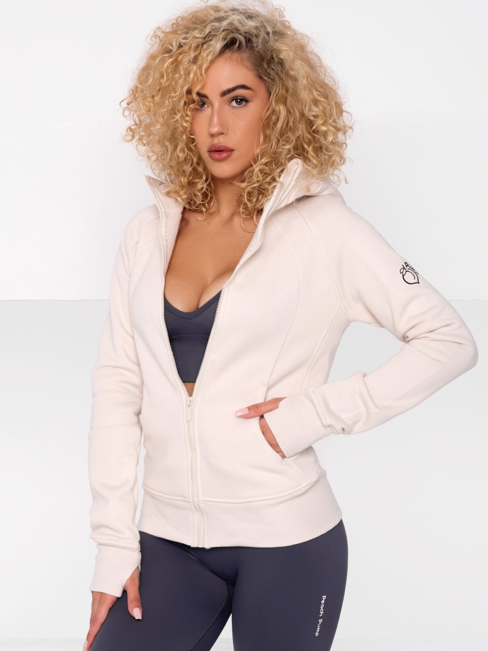 Women's sporty hoodie in beige with large hood and front zip fastening.