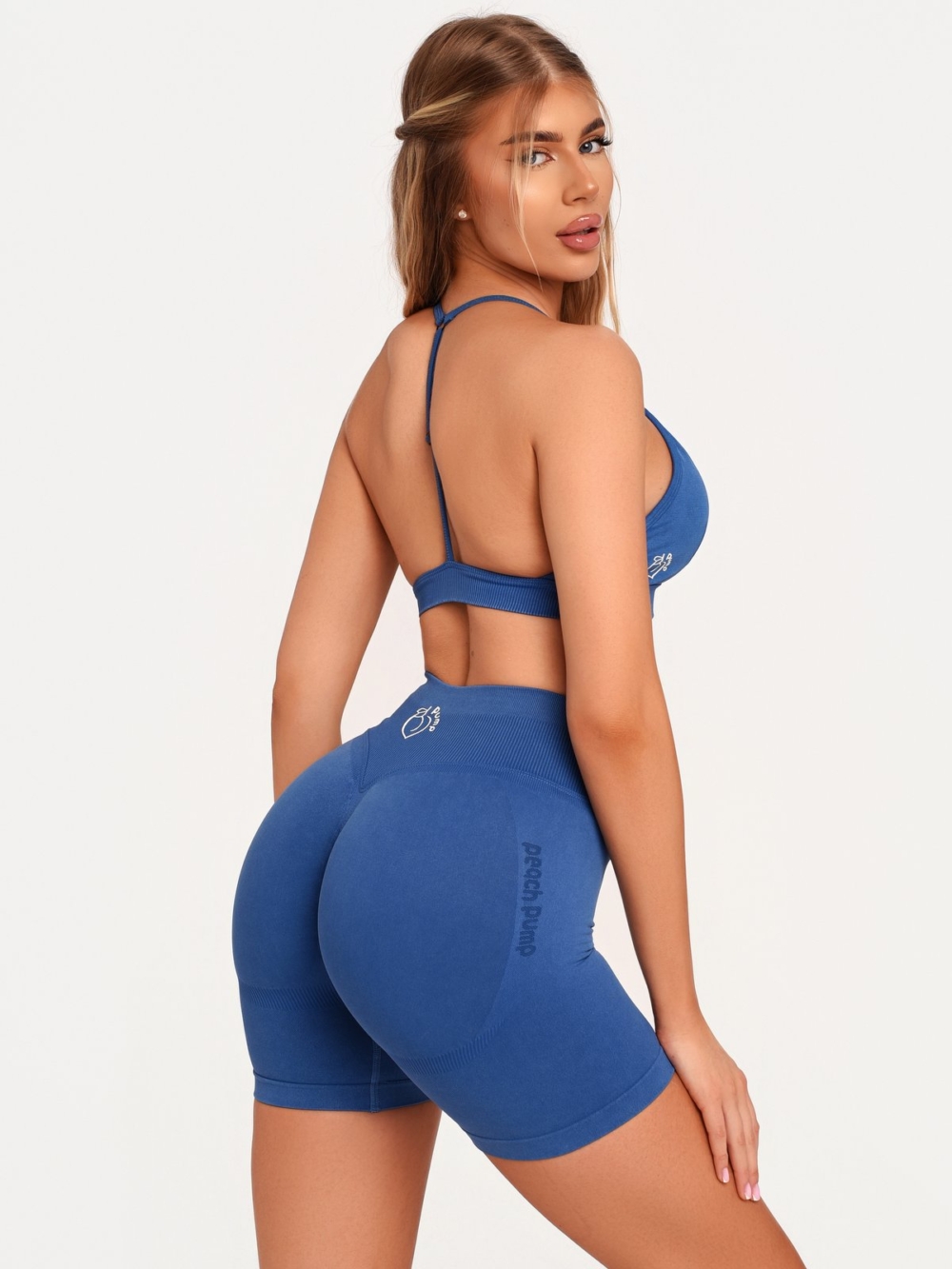 Set sportiv de damă, de culoare albastră, compus dintr-o pereche de colanți scurți cu efect Push Up și o bustieră cu susținere confortabilă.